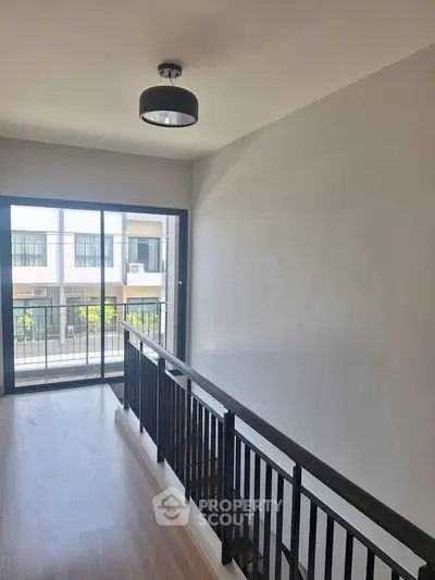 Modern hallway with sleek railing and large window offering natural light and neighborhood view.
