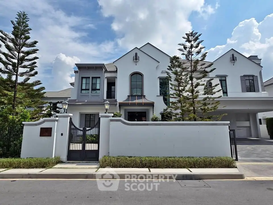Elegant modern house with white facade and lush landscaping under a bright blue sky.