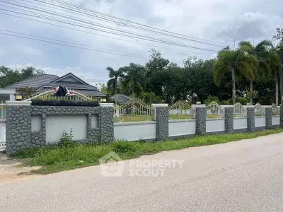 Charming suburban home with stone fence and lush greenery, perfect for family living.