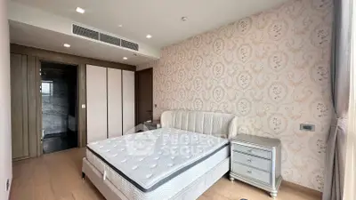 Luxurious bedroom with elegant wallpaper and modern furniture in a high-end apartment.