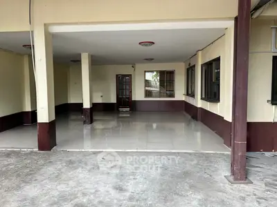 Spacious covered parking area with tiled flooring and multiple windows in a residential property.