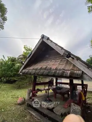 Charming rustic outdoor gazebo with wooden roof in lush garden setting.