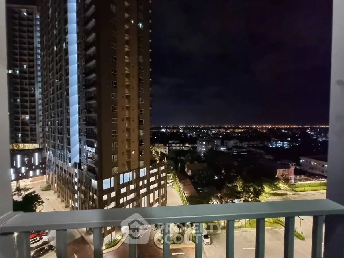Stunning night view from a high-rise balcony overlooking cityscape and illuminated buildings.