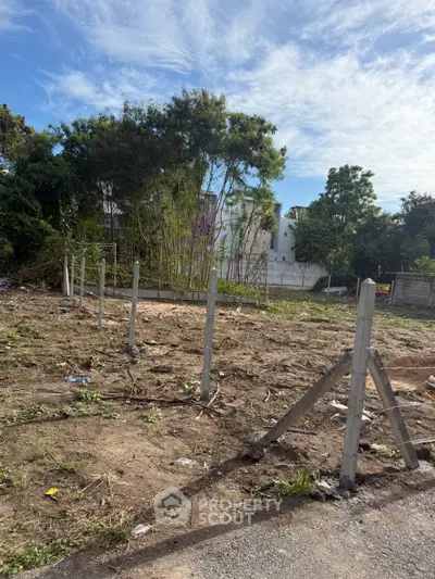 Vacant land plot with partial fencing, ideal for development in a serene neighborhood.