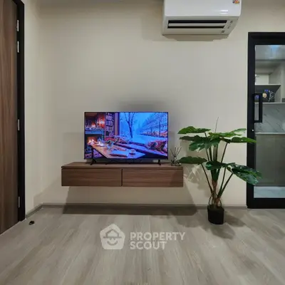 Modern living room with wall-mounted TV, air conditioning, and stylish wooden flooring.