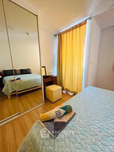 Cozy bedroom with mirrored wardrobe and bright yellow curtains, perfect for relaxation.
