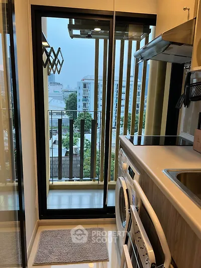 Modern kitchen with washing machine and balcony view in urban apartment
