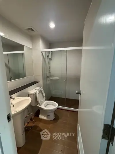Modern bathroom with glass shower enclosure and sleek fixtures in a contemporary apartment.
