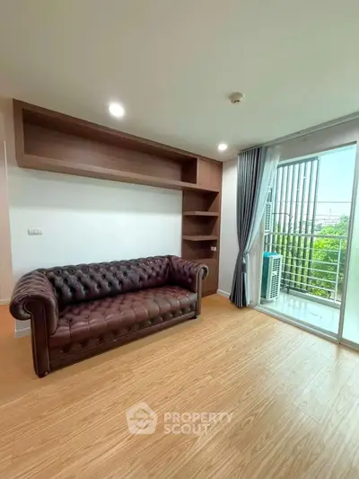 Spacious living room with elegant leather sofa and balcony view