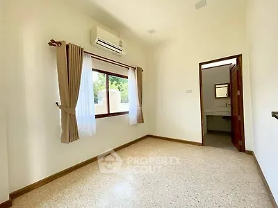 Bright bedroom with air conditioning and window view, featuring neutral decor and polished flooring.