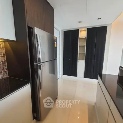 Modern kitchen with sleek cabinets and stainless steel fridge in luxury apartment.