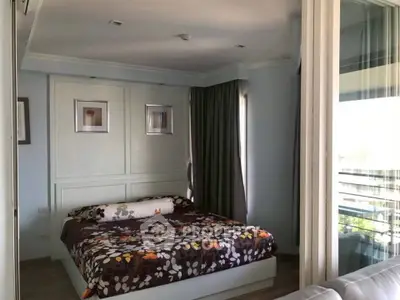 Cozy bedroom with floral bedding and large window offering natural light