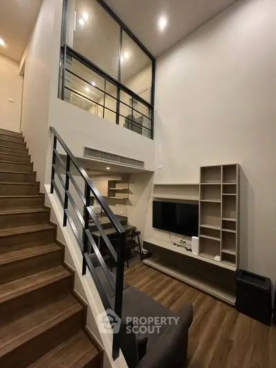 Modern loft-style living room with high ceilings and sleek staircase
