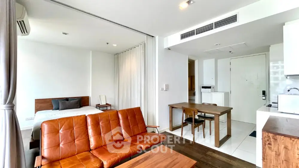 Modern open-plan studio apartment with stylish leather sofa and cozy dining area.