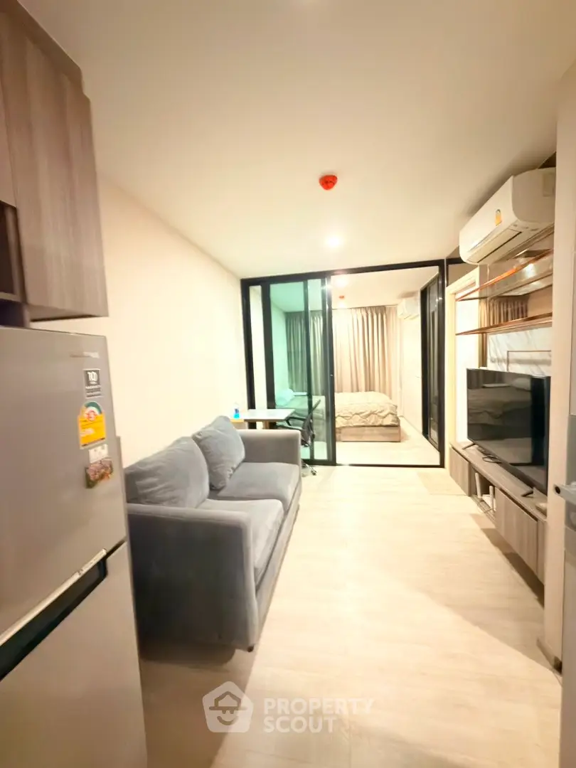 Modern apartment interior with open layout, featuring cozy living room and bedroom with glass partition.