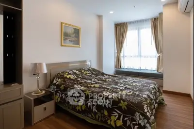 Cozy bedroom with floral bedding, large window, and elegant decor in modern apartment.