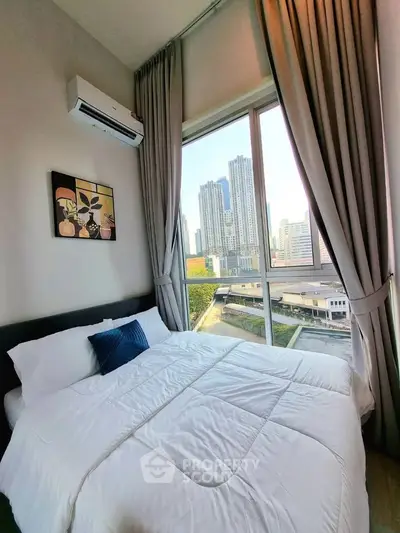 Modern bedroom with large window offering stunning city view in high-rise apartment.