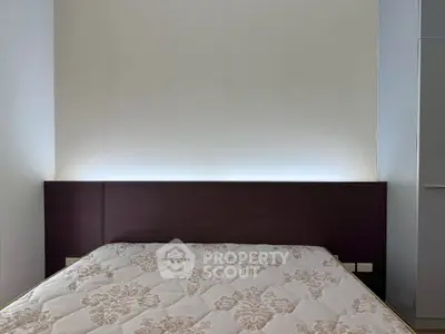 Modern bedroom with elegant headboard and floral-patterned mattress in a minimalist design.