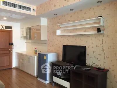 Modern living room with stylish wallpaper, sleek TV stand, and compact kitchen area.