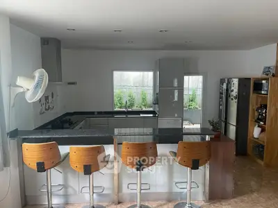 Modern kitchen with sleek design and bar seating, featuring stainless steel appliances and open layout.