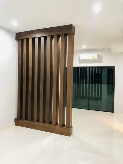 Modern interior with wooden partition and sliding glass doors in a spacious room.