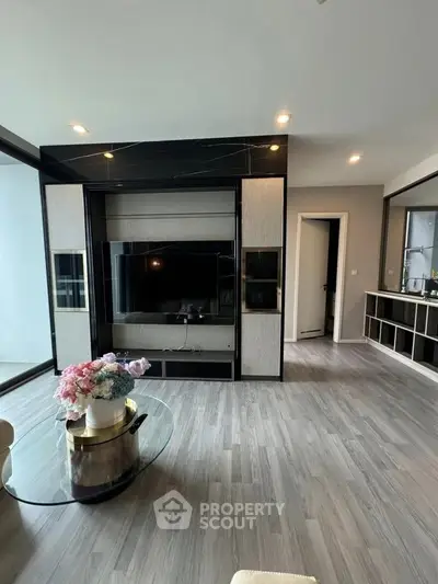 Modern living room with sleek TV unit and elegant decor, featuring large windows and stylish flooring.
