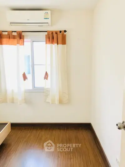 Bright empty room with wooden flooring and air conditioning, perfect for customization.