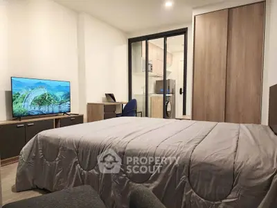 Modern bedroom with cozy decor and built-in wardrobe, featuring a TV and workspace.