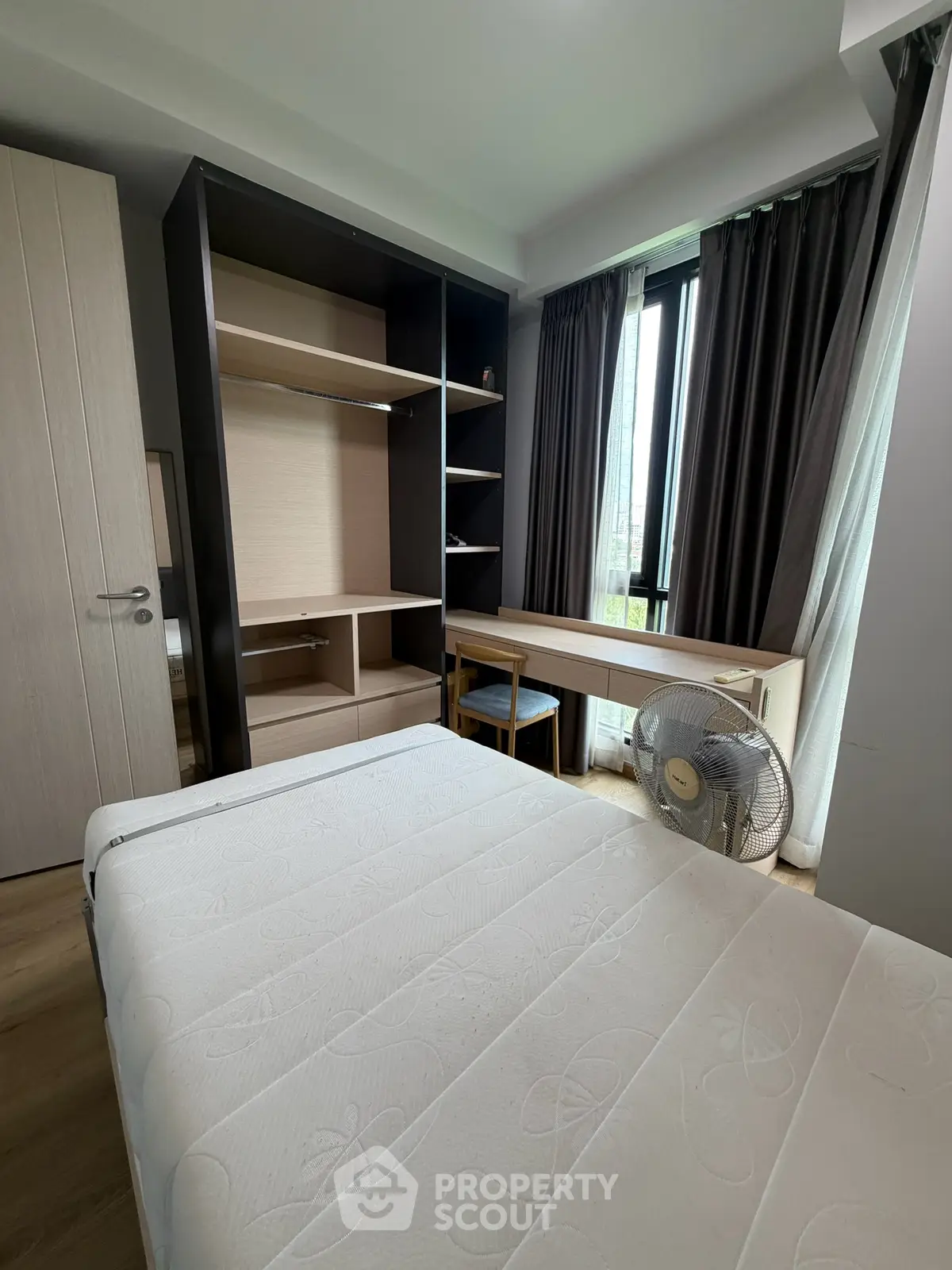 Modern bedroom with large window, built-in shelves, and desk, perfect for urban living.