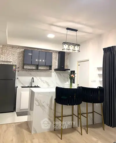 Modern kitchen with sleek design, featuring marble countertops, stylish bar stools, and contemporary lighting.