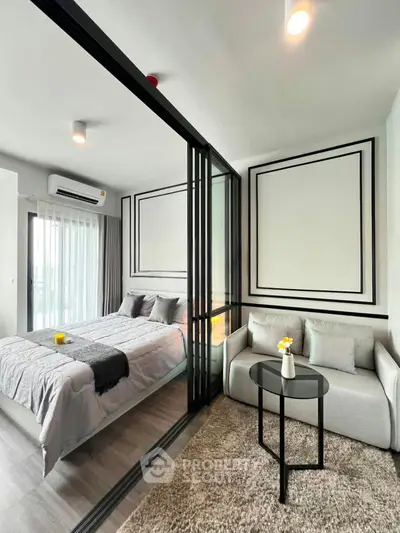 Modern bedroom with glass partition and cozy seating area in stylish apartment.