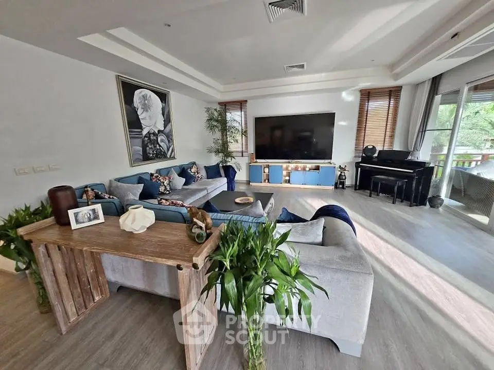 Spacious living room with modern decor and large TV, perfect for relaxation.