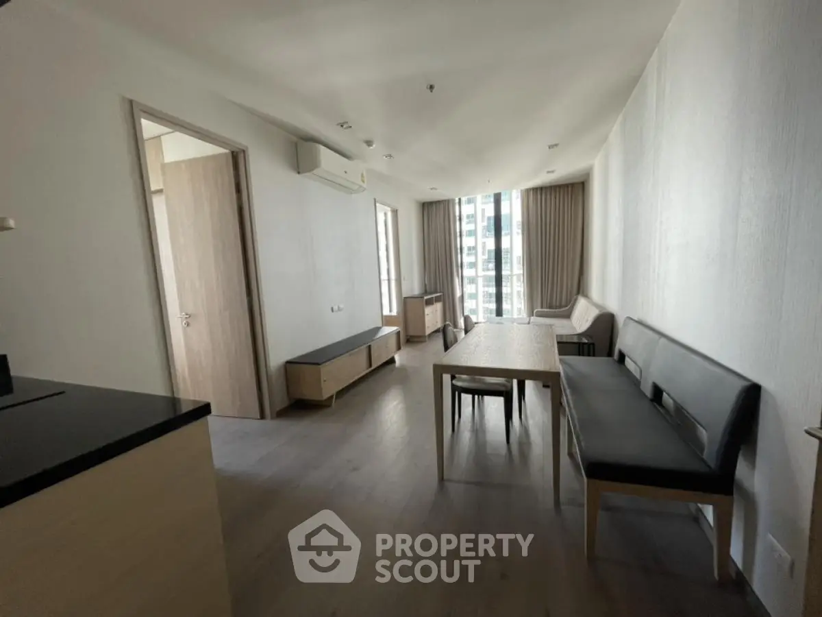 Modern living room with sleek furniture and large windows offering city views.