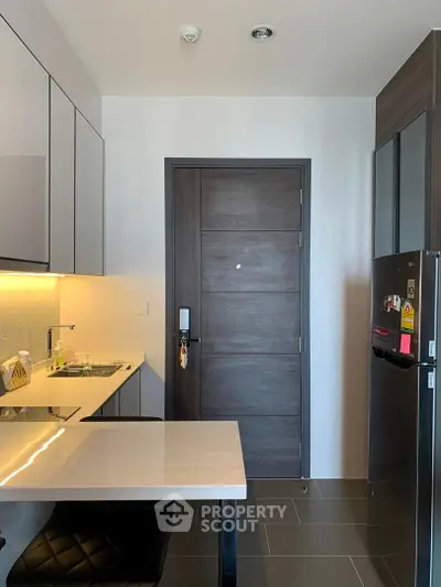 Modern kitchen with sleek cabinetry, built-in appliances, and stylish dining area in contemporary apartment.