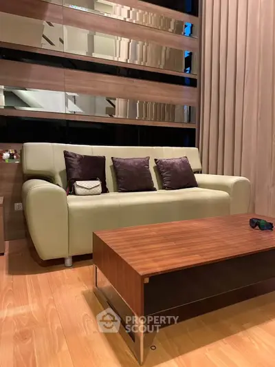 Modern living room with stylish sofa and wooden coffee table, featuring elegant decor and warm lighting.