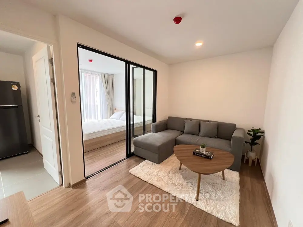 Modern living room with cozy sofa and open view to bedroom