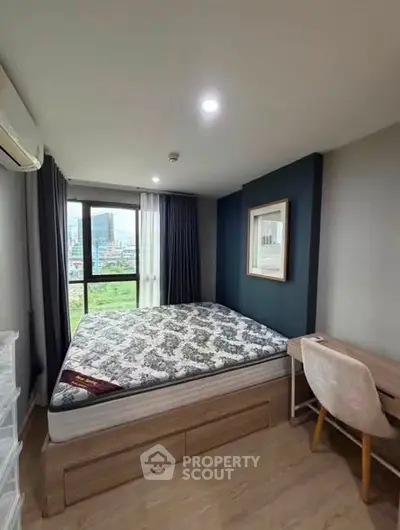 Modern bedroom with large window and stylish decor in urban apartment.