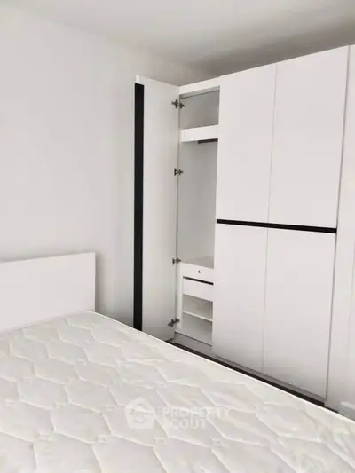 Modern bedroom with sleek white wardrobe and comfortable mattress.