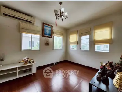 Spacious living room with wooden flooring and natural light, featuring elegant decor and air conditioning.
