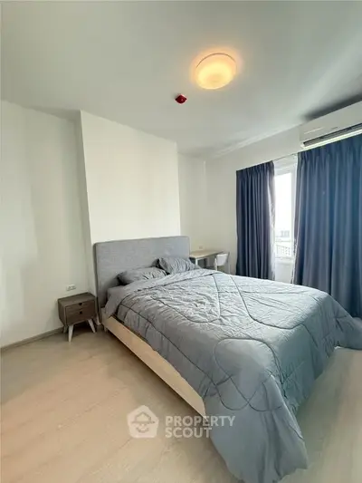 Modern bedroom with stylish gray bedding and natural light from large window.