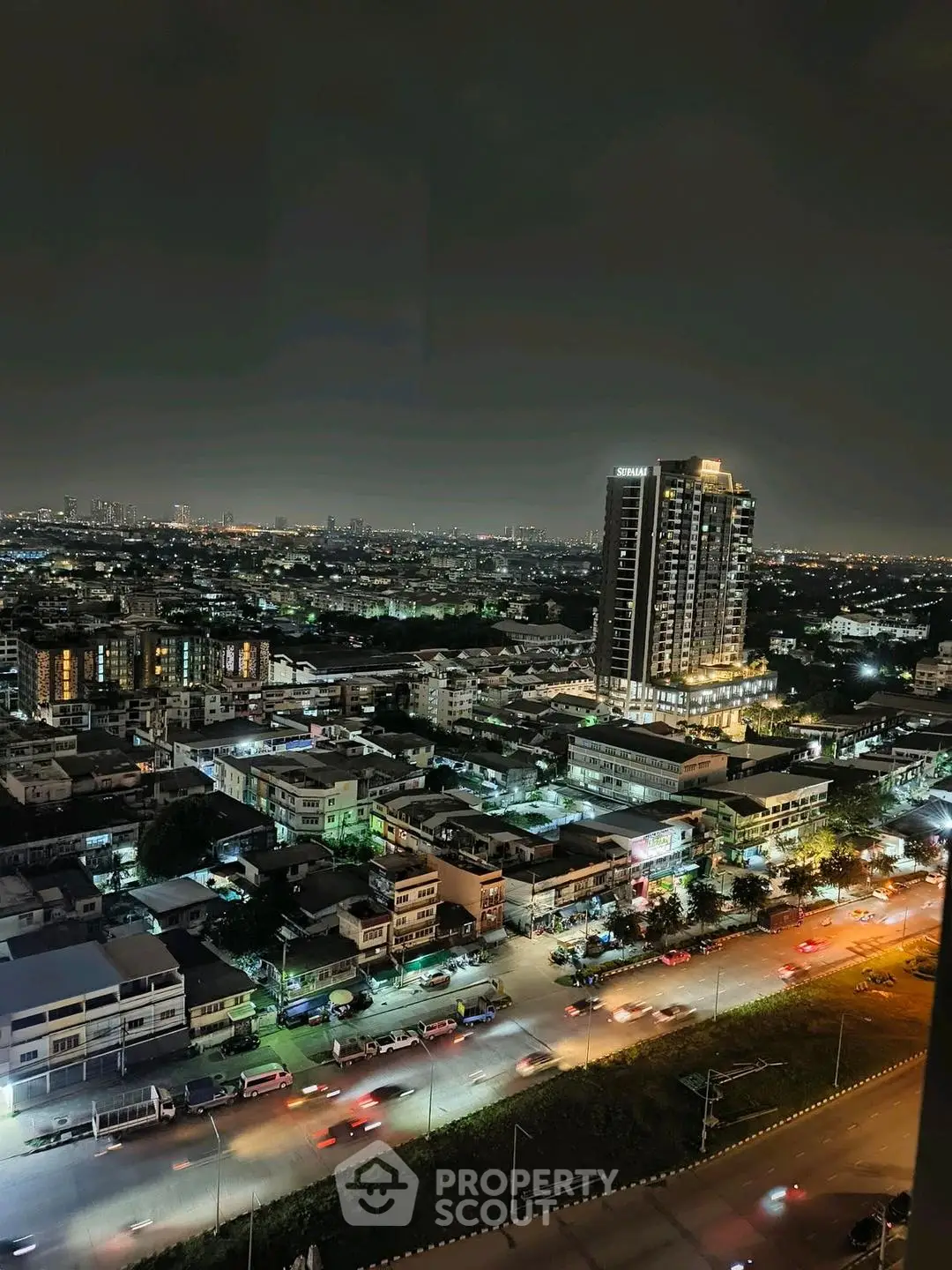 Stunning nighttime cityscape with illuminated high-rise building and bustling streets.
