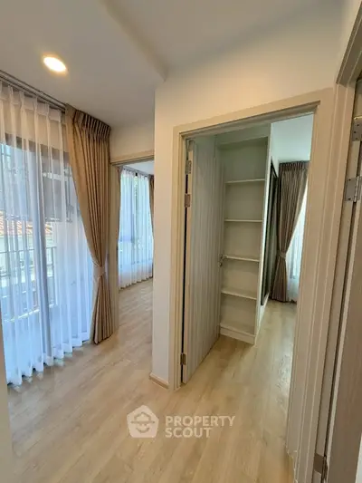 Spacious modern apartment with elegant wooden flooring and ample natural light from large windows.