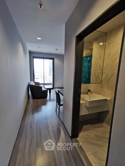 Modern apartment hallway leading to a cozy living room with city view.