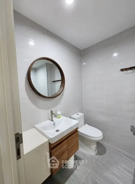 Modern bathroom with sleek fixtures and round mirror in a contemporary home.