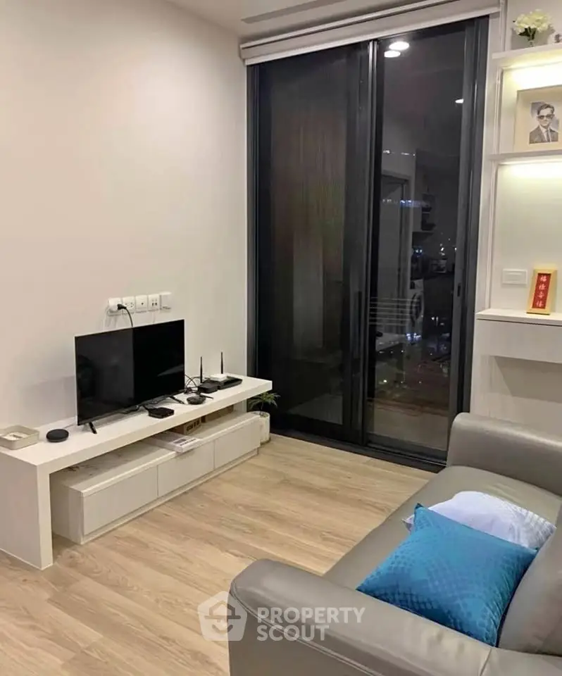 Modern living room with sleek furniture and city view through large window.