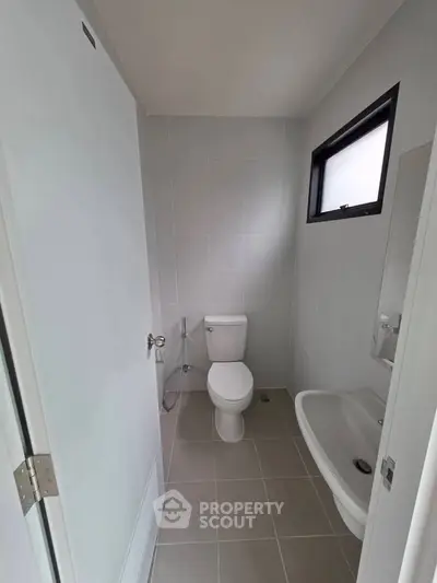 Modern minimalist bathroom with sleek white fixtures and natural light.
