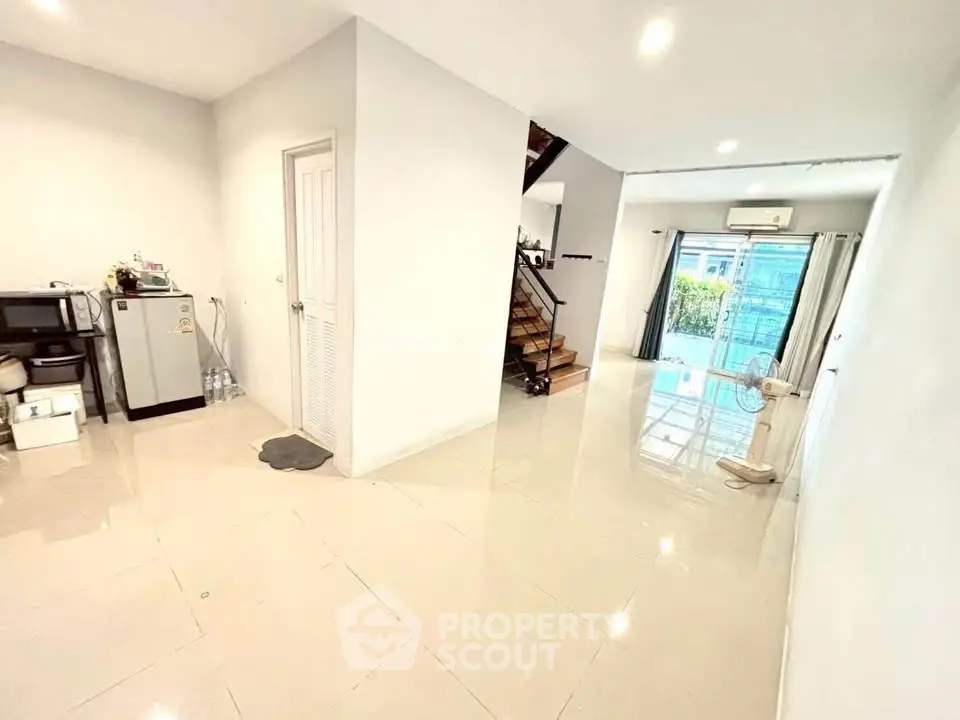 Spacious modern living room with sleek tile flooring and ample natural light, featuring a staircase and open layout.