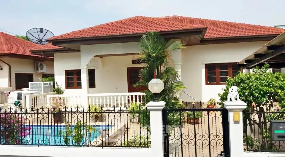 Charming single-story house with red roof, private pool, and lush garden in a serene neighborhood.