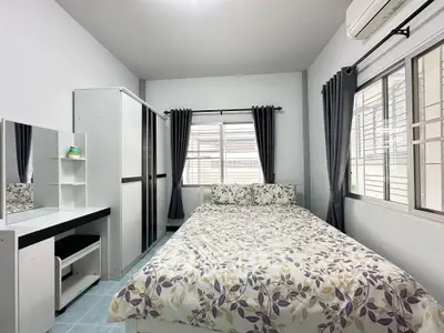 Cozy bedroom with floral bedding, ample storage, and natural light from large windows.
