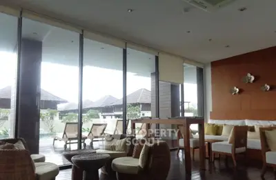 Luxurious living room with large windows and stylish furniture overlooking a serene outdoor view.